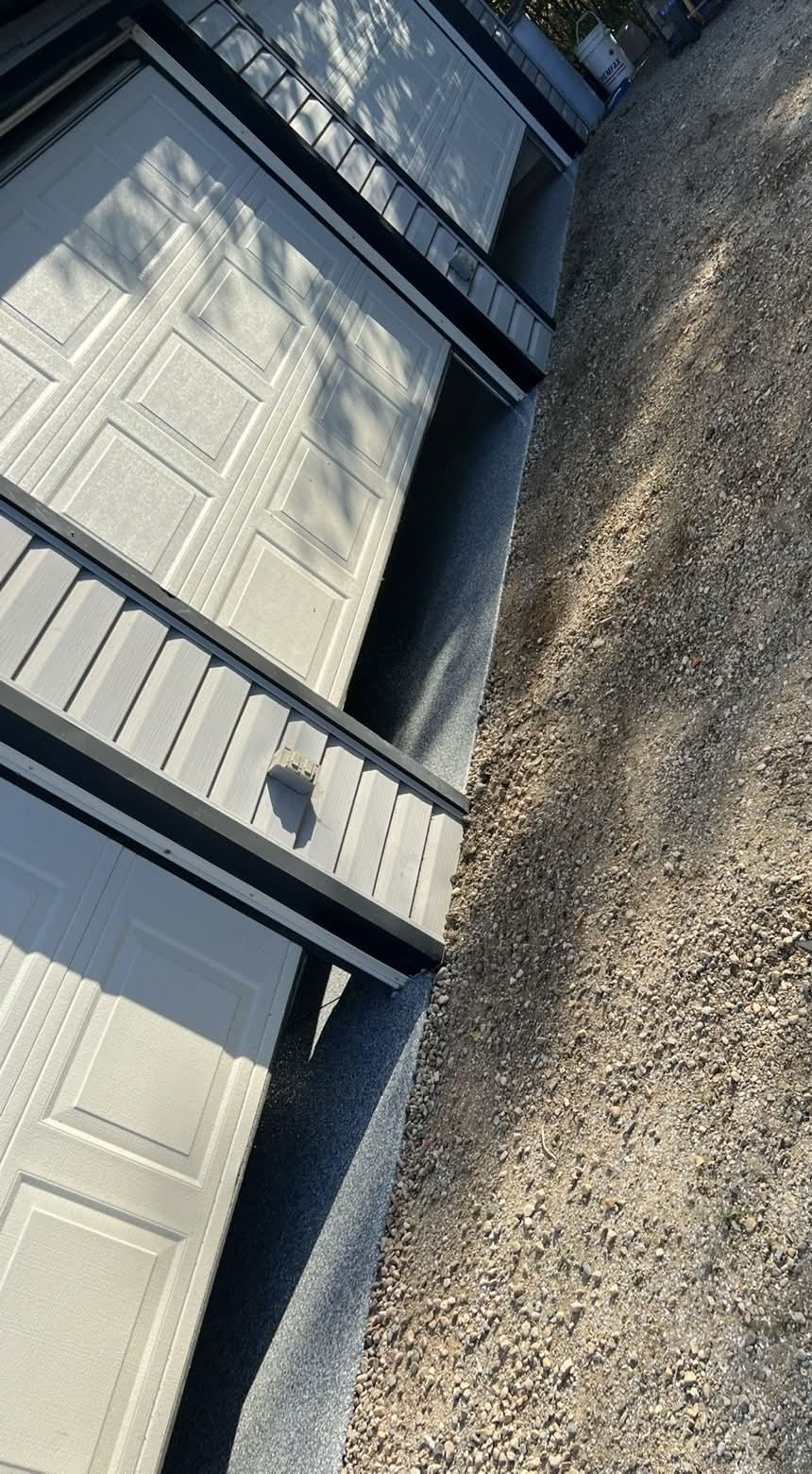 Grey flake coated thresholds outside three garage doors